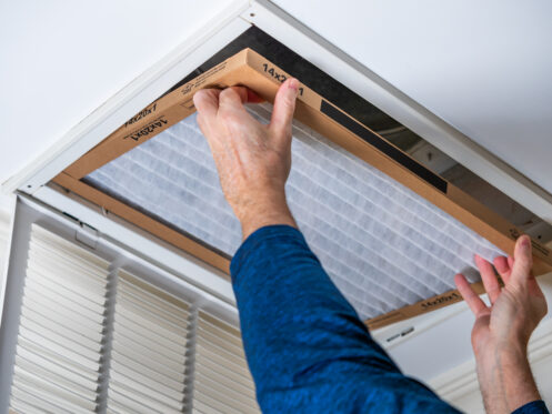 Man replacing an air filter in a Pensacola home